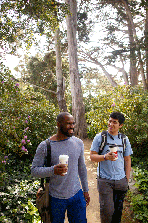 Pair of math students walking together through trees and drinking coffee