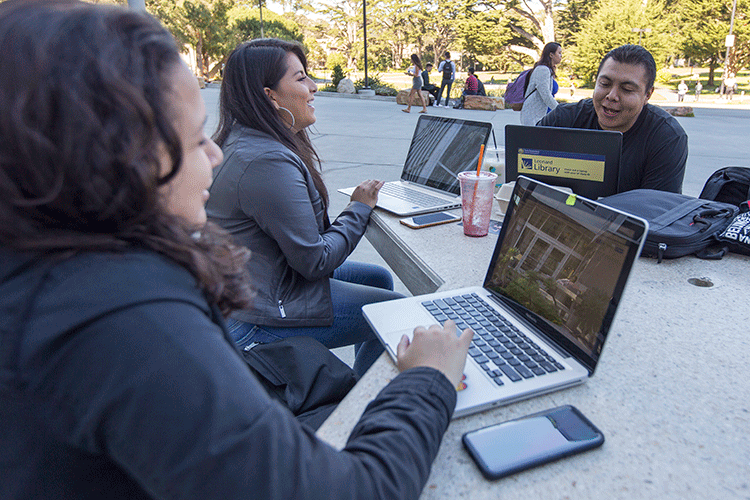 Math study group working on laptops outside the library